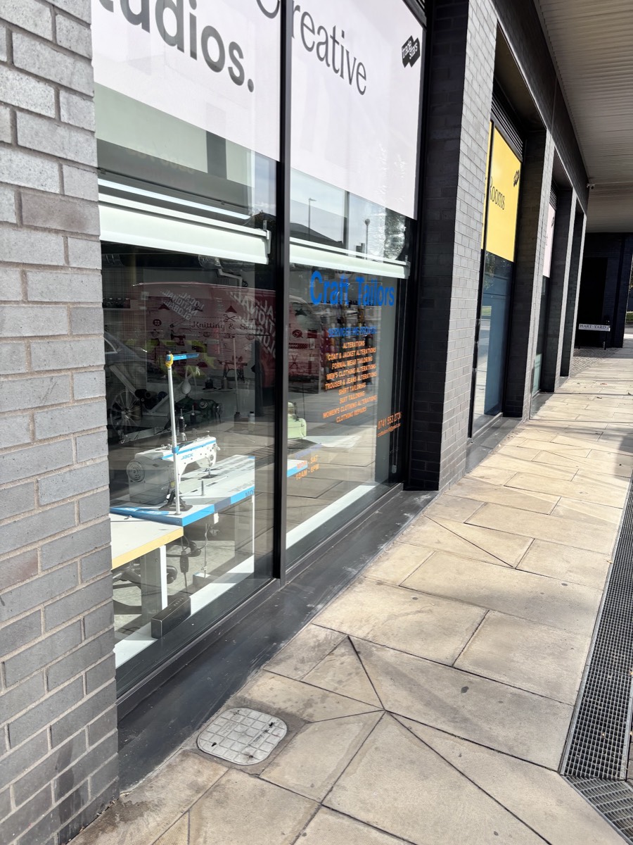 The Craft Tailors studio window on Wick Lane, Fish Island, with the services listed on the glass